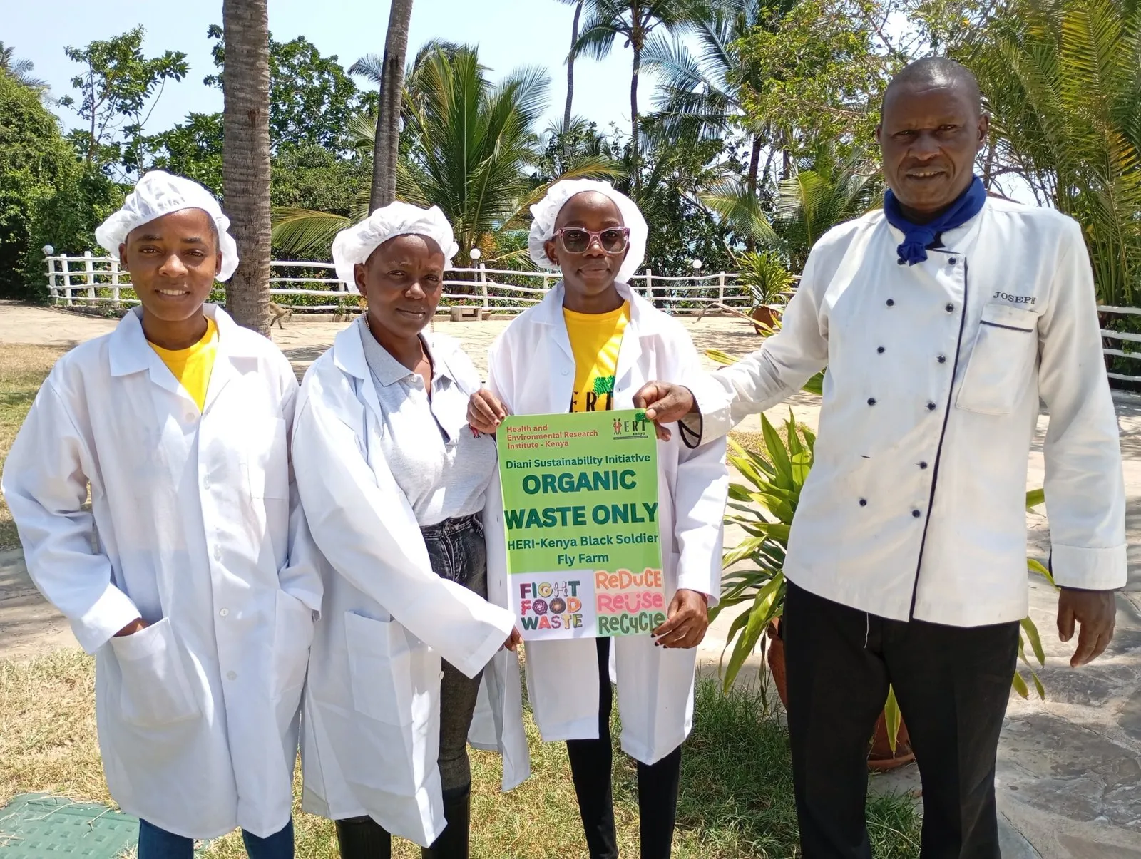 Hotel kitchen staff and a chef hold a HERI 'Organic waste only' sign